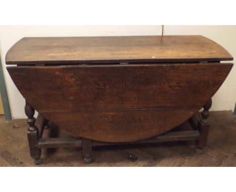 An antique oval oak gate leg dining table on turned legs with cross stretchers, approx 142cms wide, 160cms with leaves up