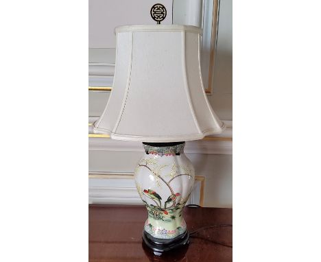 An Oriental hand painted ceramic baluster shaped lamp base decorated with parrots in a naturalistic scene, wooden plinth base