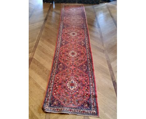 A large hand knotted Hamadan runner with five elephant foot gourds, in tones of red and blue 487cm x 60cm 