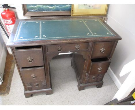 A mid 20th century oak kneehole desk with a green scriber over seven drawers, raised on bracket feet, 30h, 37 w