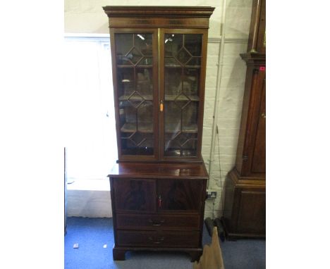 A late Victorian/early Edwardian mahogany bookcase cabinet having twin glazed doors, with cupboard and drawers below on brack