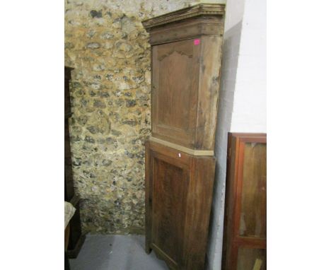 An early 20th century mahogany corner cabinet, the top with dentil moulded cornice, above a shaped, arched fielded door, belo