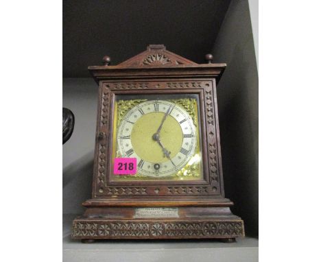 A late Victorian carved oak cased mantle clock with a silvered Roman chapter ring and brass dial, 11 h