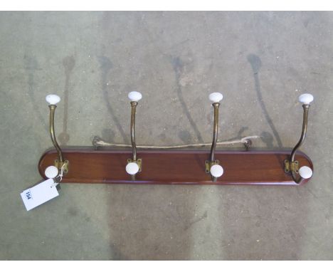 A set of four Victorian brass and ceramic coat gooks, 69cm long, in good condition 