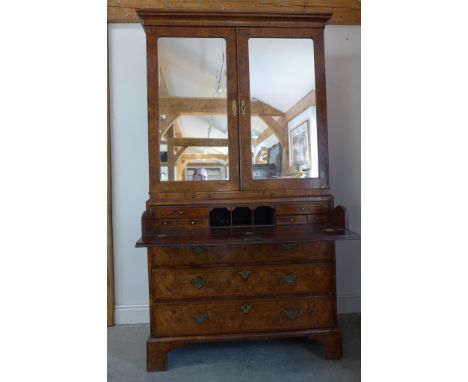 An 18th and later burr walnut secretaire cabinet, the top with two mirrored doors and an interior of sliding shelves and thre