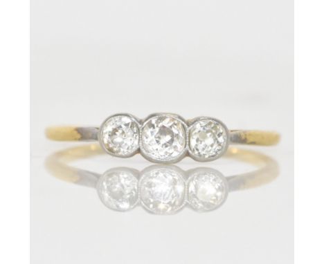 A three-stone diamond yellow metal engagement ring, claw-set, with three old-cut diamonds in a graduated setting, the central