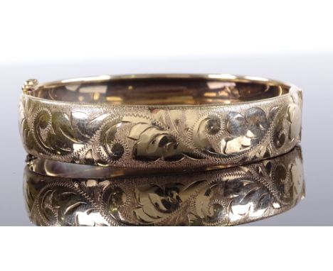 A 9ct gold hinged bangle, with engraved foliate front, band width 13.1mm, 14.6g 