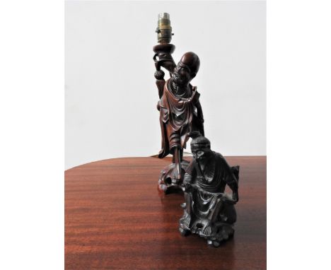 A CARVED CHINESE TABLE LAMP AND CARVED CHINESE FIGURE 20TH CENTURY modelled as Lohans 