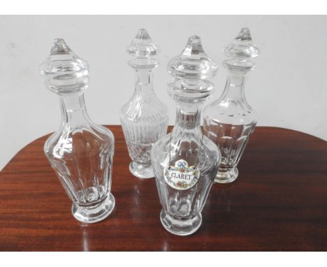 FOUR CUT GLASS DECANTERS WITH STOPPERS, one with a ceramic decanter label, 33cm high 