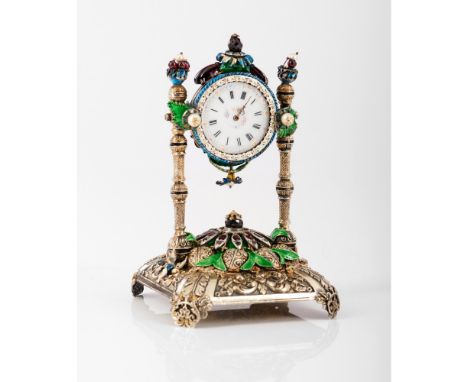 A tabletop clockSilverEngraved and chiselled decorationPolychrome enamel applied elementsSet with cultured pearls, glasses, 1