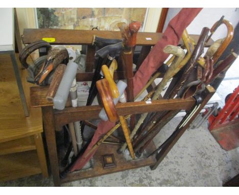 A 1930s stick stand, a quantity of miscellaneous walking canes and a fishing rod 