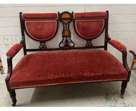 An Edwardian mahogany two seater salon sofa upholstered in red.