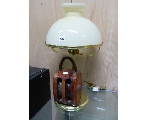 A BRASS TABLE LAMP MOUNTED WITH A WOODEN PULLEY AT ITS BASE AND WITH A LEMON GLASS SHADE.   H 61cms.