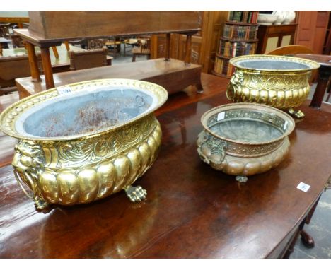 A PAIR OF CONTINENTAL ANTIQUE BRASS PLANTERS, EACH WITH OVAL RIMS ABOVE LION MASK AND RING HANDLES, LOBED BODIES AND THREE PA