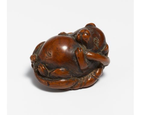 NETSUKE OF A TANUKI ON A LOTUS LEAF.  Japan. 19th c.  Tagua nut, carved and stained dark brown. H.3cm, w.4cm. Condition A/B. 