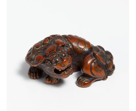 NETSUKE: RECUMBENT SHISHI WITH MOVEABLE BALL IN THE MOUTH.  Japan. 18th c.  Reddish brown wood, carved and stained dark. L.4.