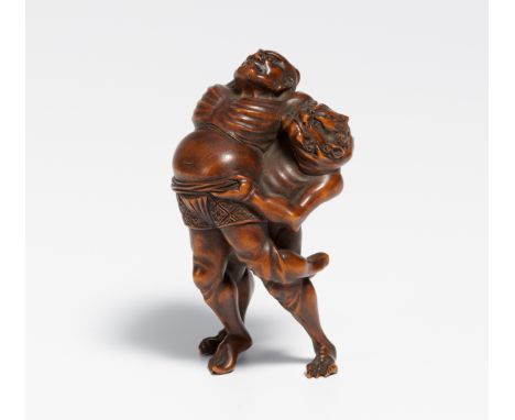 NETSUKE OF TWO SUMÔTORI AT KAWAZU.  Japan. 19th c.  Dark hardwood, finely carved. Under the foot denoted: Gyokuzan. H.6cm. La