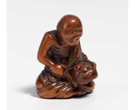 NETUSKE: CARVER WITH USOBUKI MASK.  Japan. Early 19th c.  Boxwood, carved and partly stained dark. H.3.7cm. Condition A/B.Spe