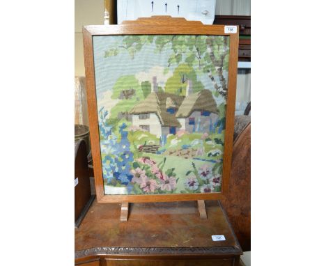 C20th fire screen with an embroidered panel of a countryside thatched cottage W47.5cm X H65.5cm 