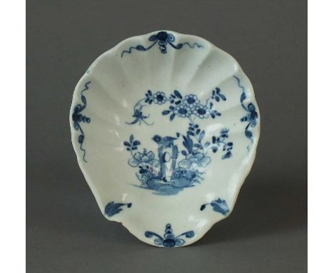 A Worcester scallop shell dish circa 1756-68 painted in blue with the Two Peony Rock Bird pattern with a bird perched on a ta