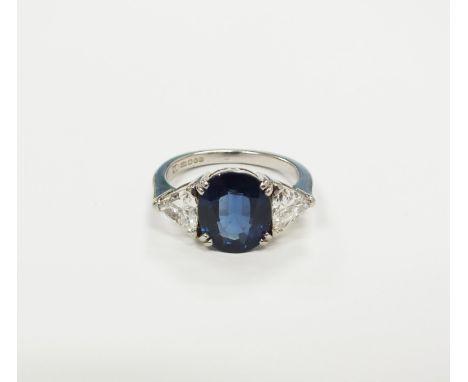A platinum three stone sapphire and diamond ring, designed as a central oval mixed cut sapphire, flanked to each side by a tr