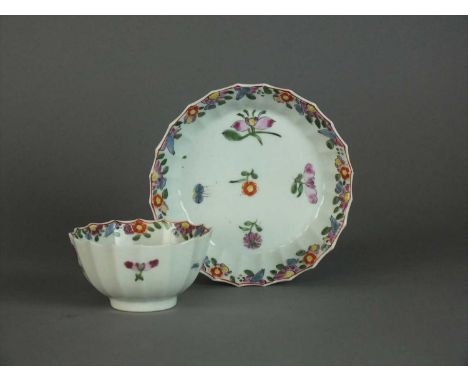 A Worcester teabowl and saucer circa 1768 of 'Warmstry Fluted' shape with a barbed rim, painted in bright enamels with a bord