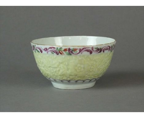 A Worcester yellow ground teabowl circa 1768 with 'chrysanthemum' pattern moulding in low relief enamelled over with a wide b