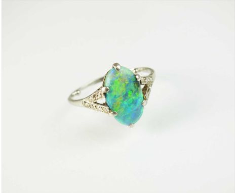 An Art Deco opal and diamond ring, designed as a central oval opal plaque claw set in white metal to diamond set split should