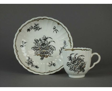 A rare Worcester fluted coffee cup and saucer circa 1778-80, enamelled in black with Chinese floral sprays with gilt accents,