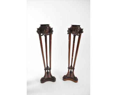 A pair of 19th century mahogany trefoil torcheres in the Adam style, each with circular platform tops with flared rims above 