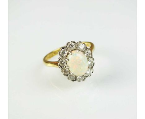 An 18ct gold opal and diamond cluster ring, designed as a central oval opal claw set within a border of ten brilliant cut dia