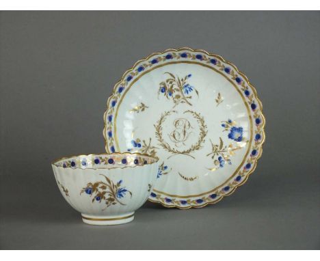 A Caughley polychrome fluted tea bowl and saucer circa 1790, decorated with monogrammed initials in gilt between a laurel wre
