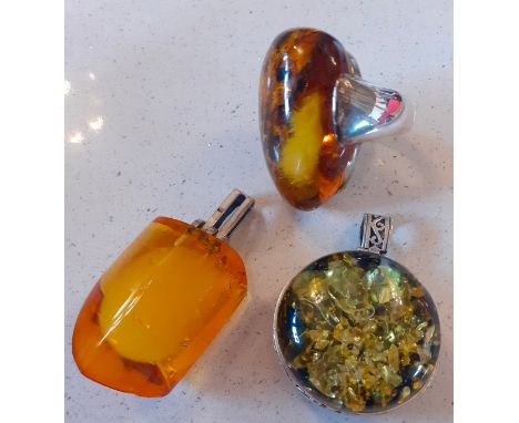 A contemporary oversized amber ring on silver mount, stamped 925 together with a Baltic green amber pendant on white metal mo