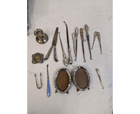 Silver handled button hooks, glove stretcher, sugar tongs, dwarf candlestick, manicure item and three photograph framesLocati
