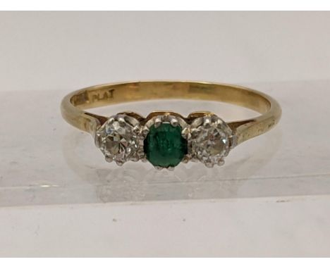 An 18ct platinum ring set with two diamonds and a central emerald size P, 2.9g Location: 