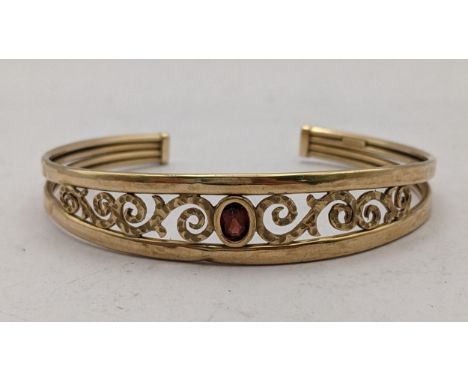 A 9ct pierced bangle having scroll work design and inset with Citrine , 6.1gLocation: 