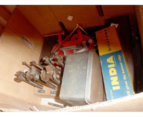 A box containing woodworking tools comprising sharpening stones, clamps, augers and a Woden dovetail jig