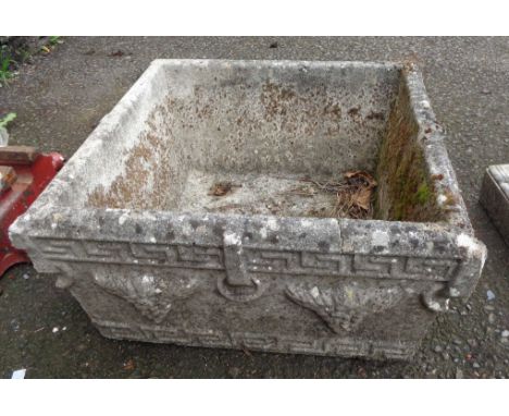 A square concrete garden planter with grapevine decoration