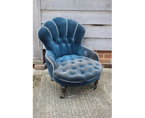 A late 19th century low seat occasional chair, button upholstered in a blue velvet, on turned and castored supports 