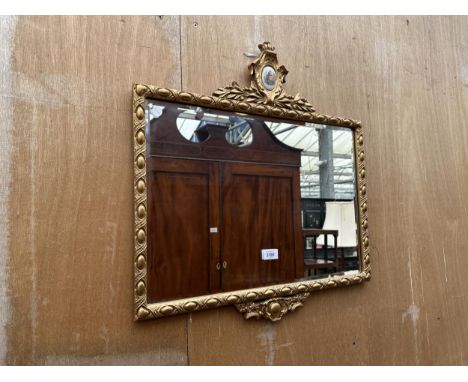 A GILT FRAMED WALL MIRROR WITH CERAMIC PLAQUE AND BEVEL EDGE