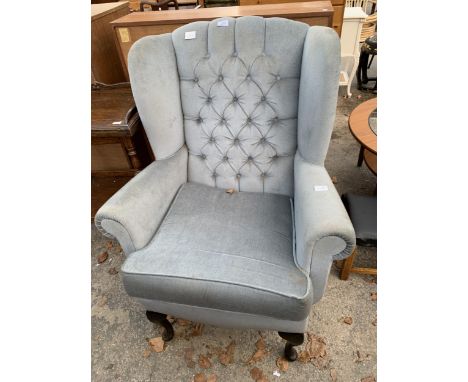 A WINGED FIRESIDE CHAIR WITH BUTTON BACK ON FRONT CABRIOLE LEGS
