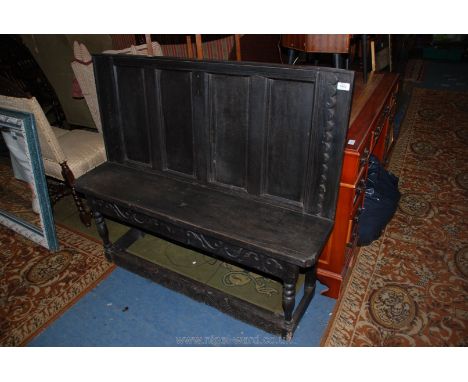 An antique style Oak Bench seat with four panel back, single plank seat, carved frieze, standing on carved legs with stretche