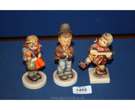Two Goebel figures, one of a girl playing a banjo, the other a boy playing a tin whistle (chips to hat) and a little girl wit