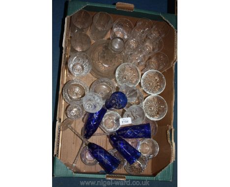 A box of glasses including blue glass champagne flutes, brandy balloons, tumblers, etc., and a decanter 