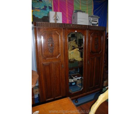 A 1940's Jacobean style triple Wardrobe with moulded cornice, over central full length bevel plated mirrored door, flanked by