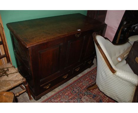 A Georgian Oak Mule Chest, having two plank lid, three panel front over two lower drawers, brass handles and on square feet. 
