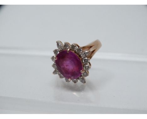 Ruby and diamond ring - A .750 yellow gold ring set a large oval cut faceted ruby, length 41mm, surrounded by a line of diamo