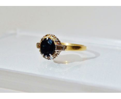 An 18ct gold ring set an oval sapphire, length 0.75cm, the shoulders set baguette diamonds, size N/O.