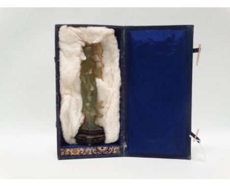 Jade - A carved figure of a woman holding a branch and leaf, standing on a pierced oval hardwood four footed socle, the whole