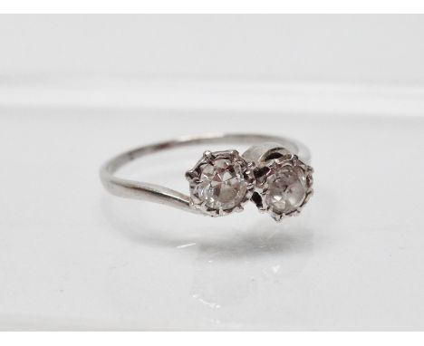 A platinum and diamond crossover ring - A platinum ring set two diamonds, each of ?? cts approximately, size O.